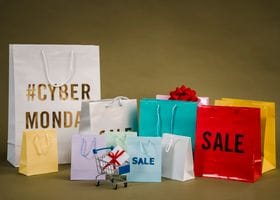 Colorful shopping bags with Cyber Monday and sale text, featuring a mini cart with gifts.